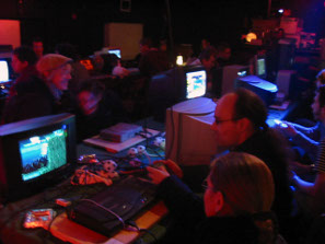 Telespielomat 2004: Dunkler Raum mit bunten Lichtern und vielen Konsolen